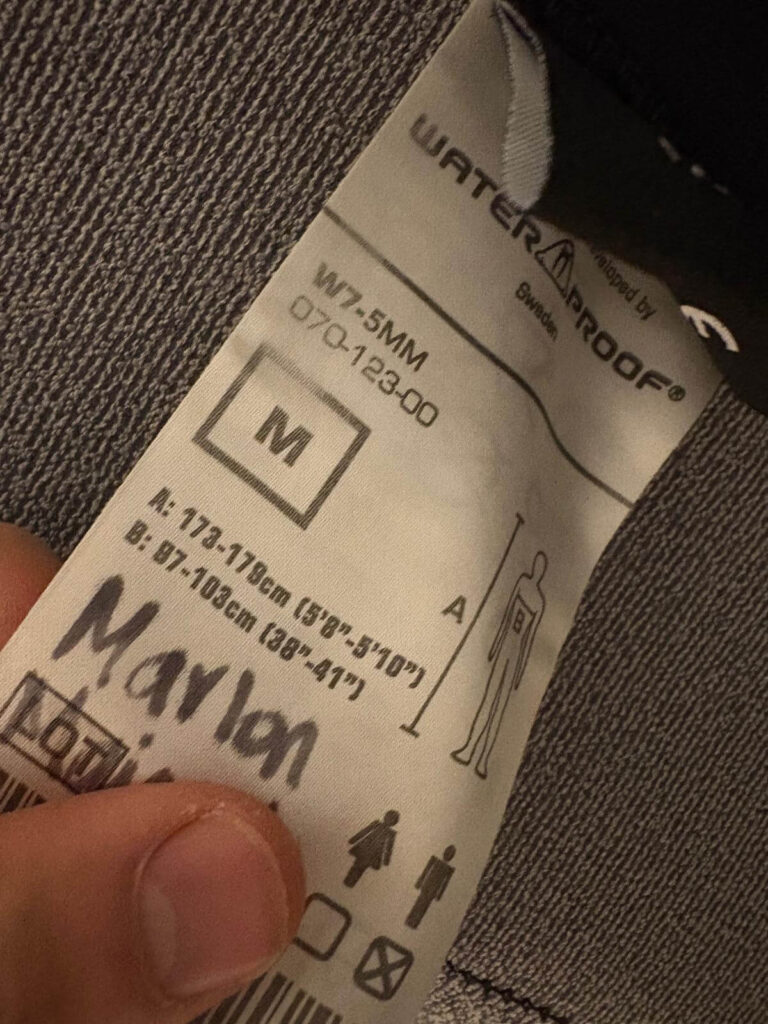 Mit Acrylmarker Edding beschriftetes Ettiket eines Neoprenanzugs