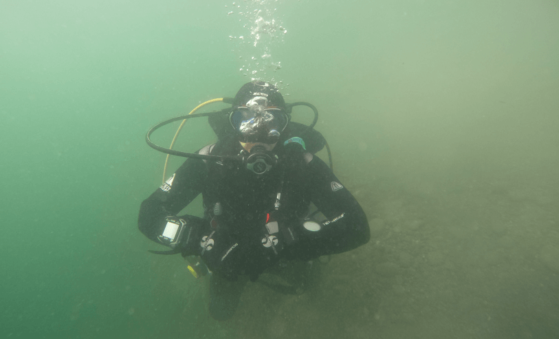Taucher schwebt ruhig im horizontalen Trim unter Wasser, entspannte Haltung und gleichmäßige Atmung zur Reduzierung des Luftverbrauchs.