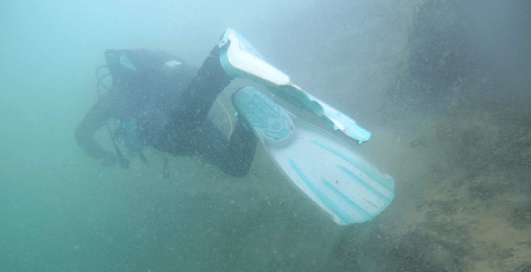Taucher testet weiß türkisene Tauchflossen unterwasser