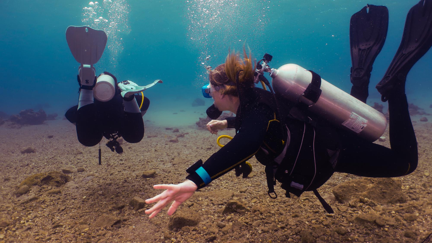 Zwei Taucher am Meersgrund machen sich über die Gefahren beim Tauchen bekannt