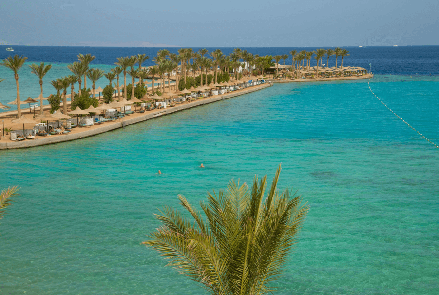 Langezogene Insel mit Palmen in blauem Wasser umgeben von Korallenriffen