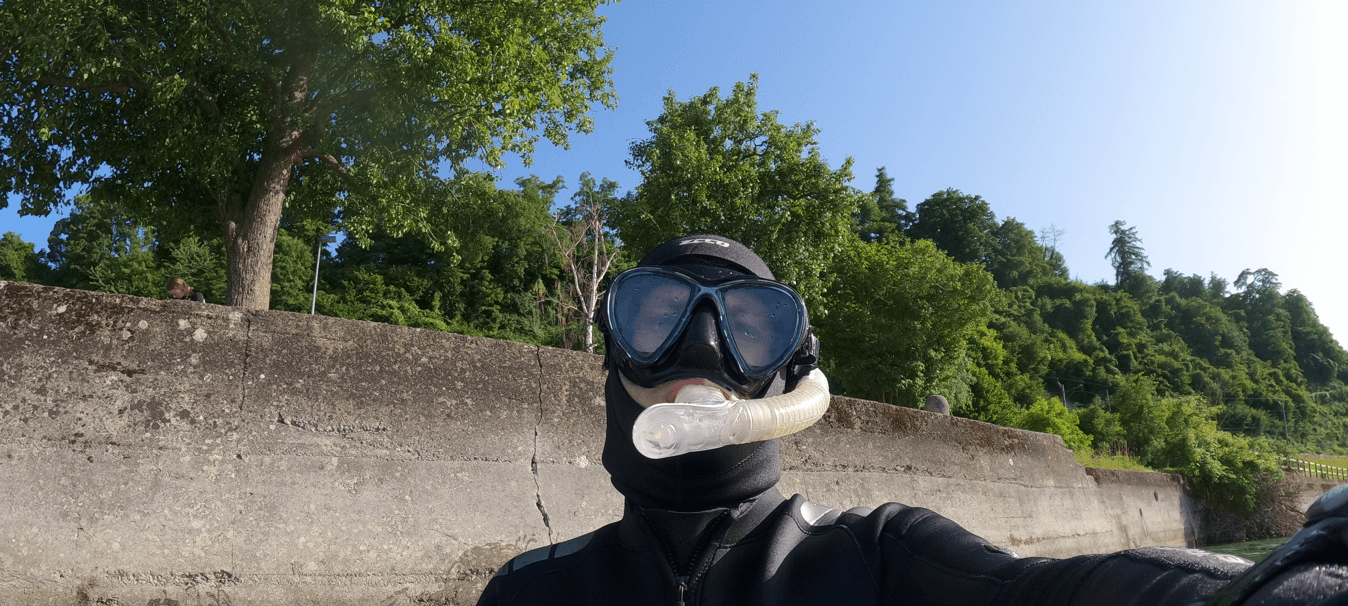 Schnorchler im Neoprenanzug testet ein schwarz weißes Schnorchelset