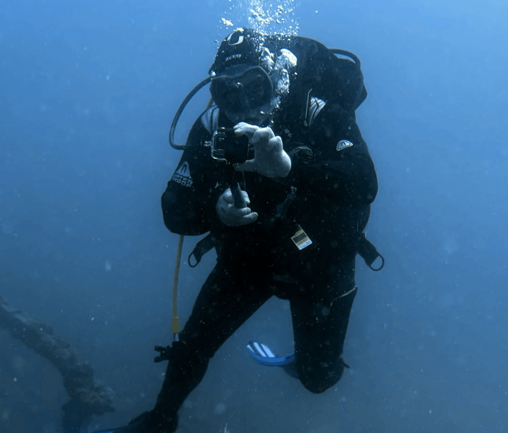 Taucher bedient Unterwasser eine GoPro im Tauchgehäuse