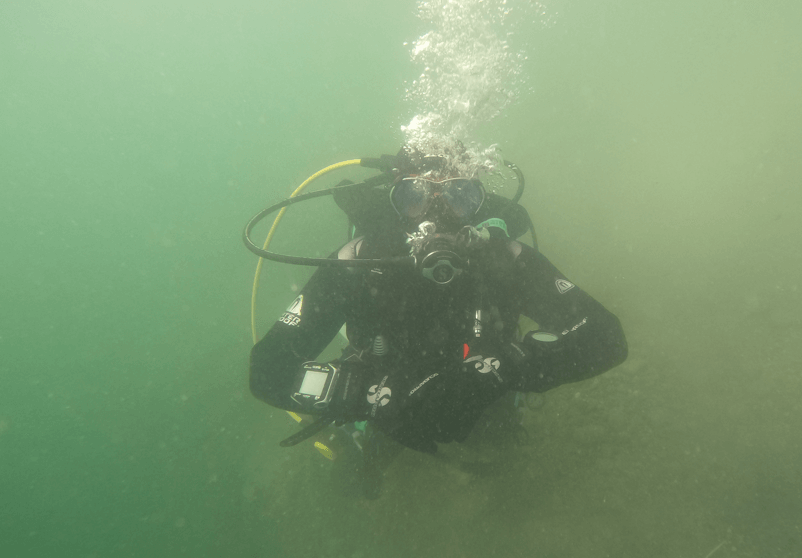 Taucher trägt dicke Neoprenhandschuhe im trüben Bodensee