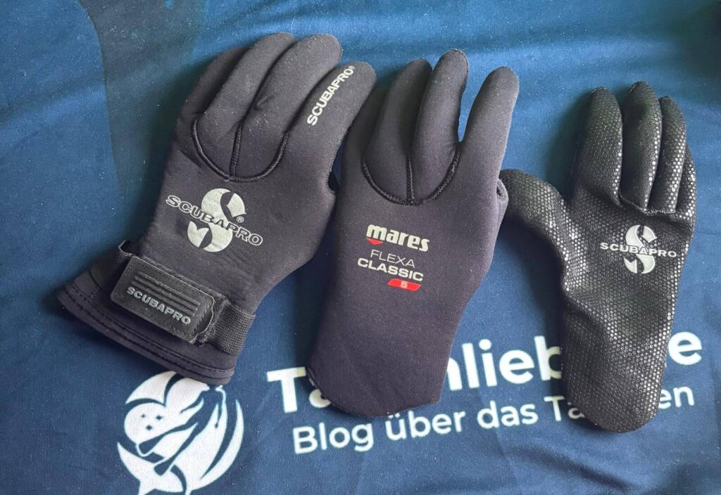 Drei einzelne Neopren Tauchhandschuhe mit unterschiedlicher Neoprenstärke  liegen nebeneinander