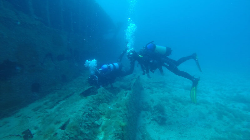 Zwei Taucher schwimmen neben einem Wrack in Europas Gewässern und erkunden die Überreste des versunkenen Schiffes.