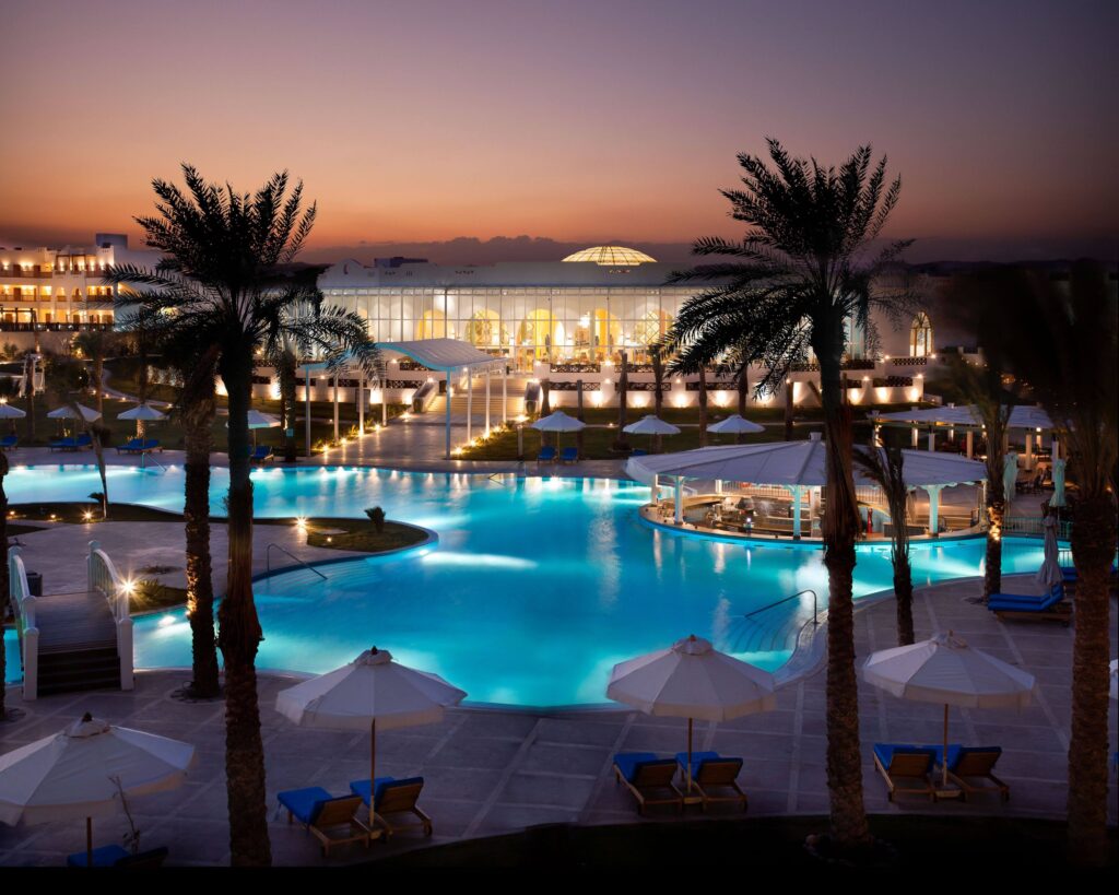 Großer Poolbereich im Hilton Marsa Alam Nubian Resort mit Sonnenschirmen und Palmen