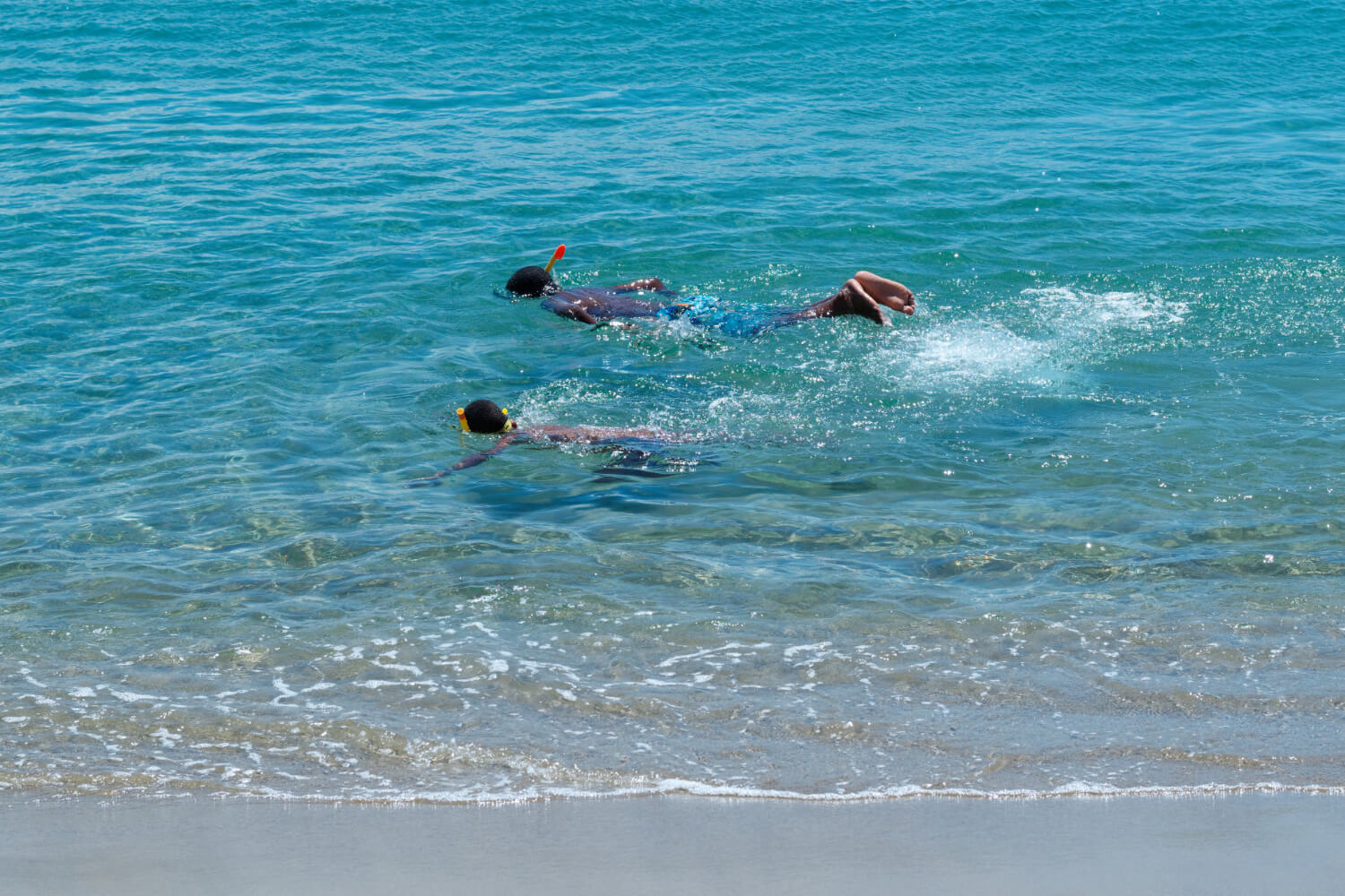 Zwei Kinder schnorcheln am Strand im flachem Wasser