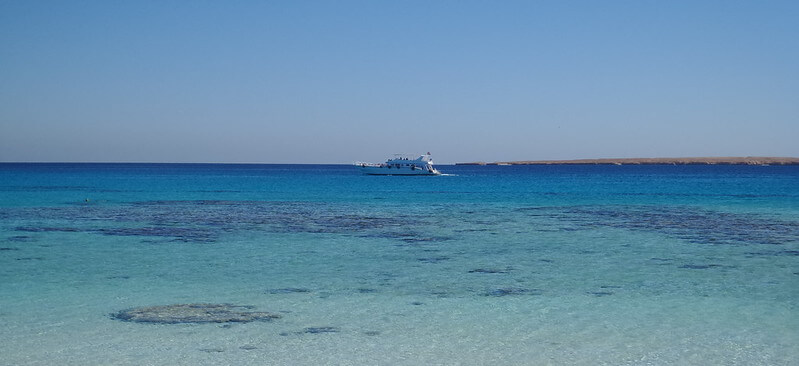 Hausriff mit Boot im Hintergrund aus Sicht des Strandes