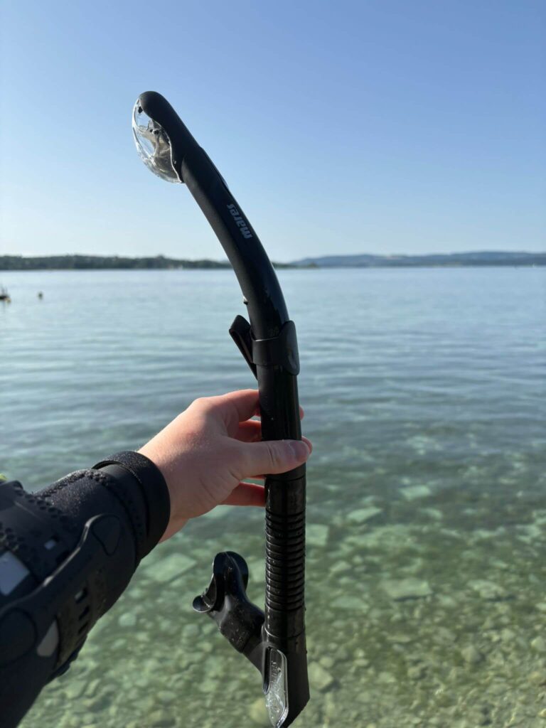 Mares Ergo Dry Schnorchel in der Hand mit See im Hintergrund