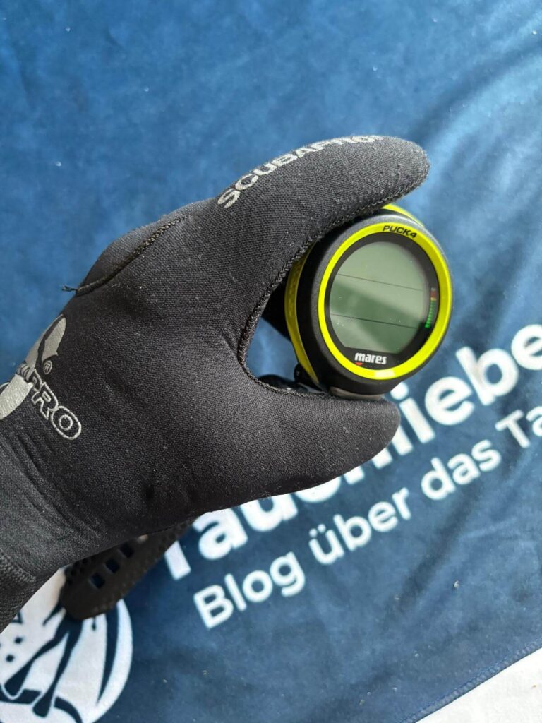 Tauchcomputer in Neoprenhandschuh, Knopf wird gedrückt