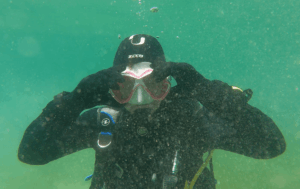 Taucher fixiert beim Ausblasen die Tauchmaske am oberen Rand unter Wasser.