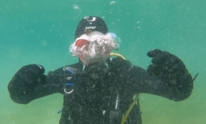 Taucher bläst unter Wasser die Maske aus und drückt Wasser durch Nasenatmung nach unten heraus.