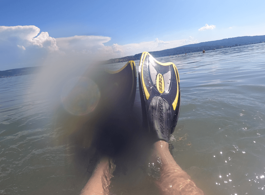 Schnorchelflossen ragen an der Wasseroberfläche in die Luft, Beine im See