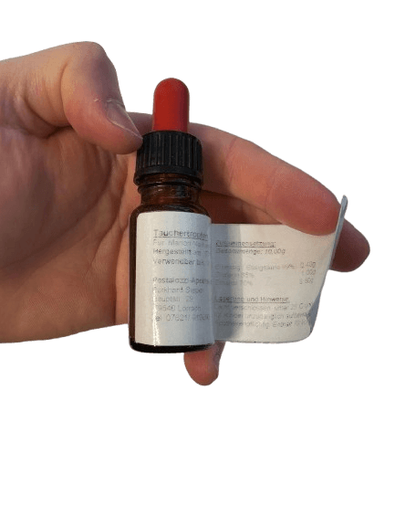 Taucherohrentropfen mit Ettikett werden in der Hand gehalten