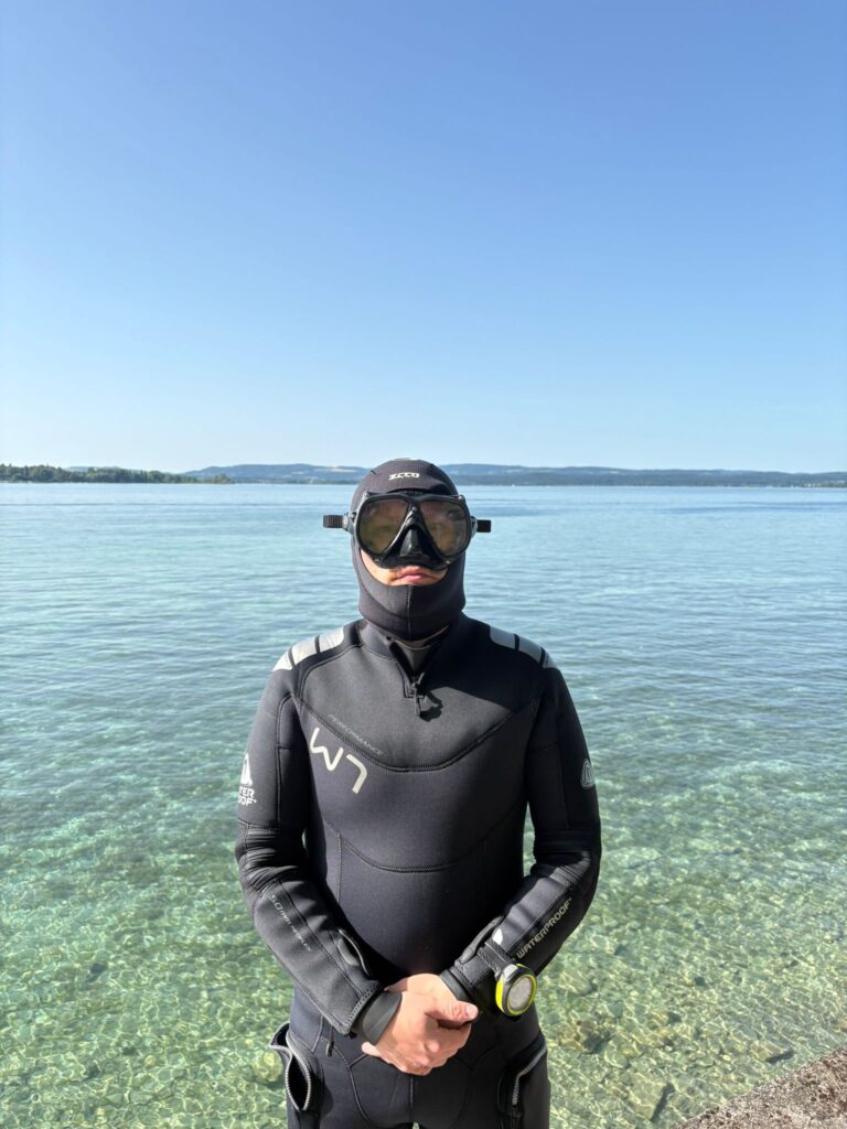 Taucher mit Waterproof W7 5mm steht am Ufer vor dem Tauchgang