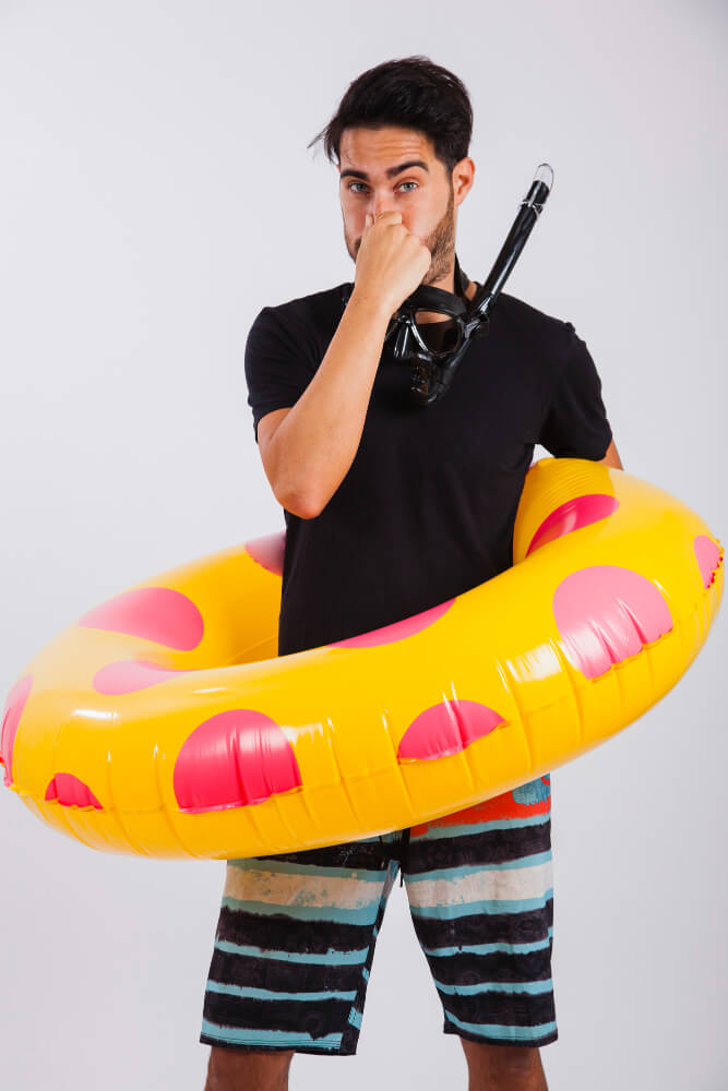 Taucher macht im Badeoutfit mit Schwimmring einen Druckausgleich an Land