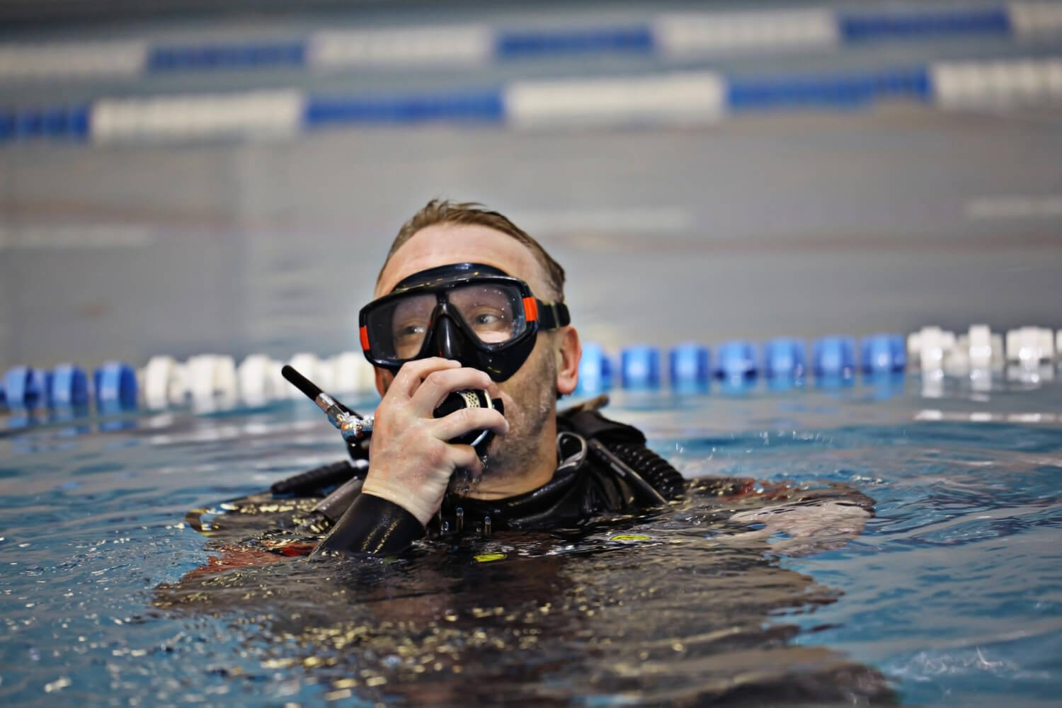 Taucher mit schwarzer Tauchmaske und Atemregler an der Wasseroberfläche beim Indoor Tauchen in Deutschland
