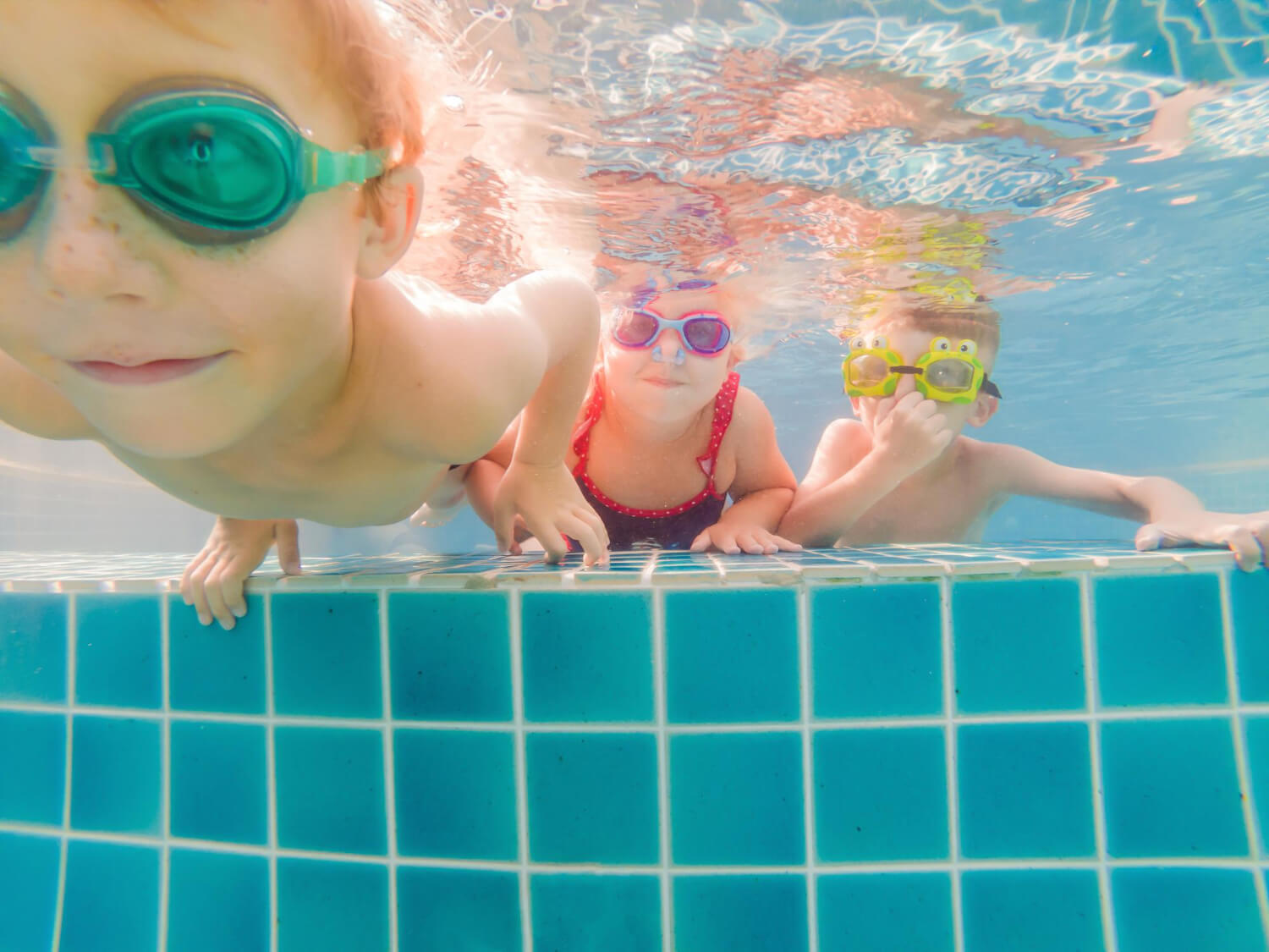 3 Kinder spielen Unterwasser in einem Pool