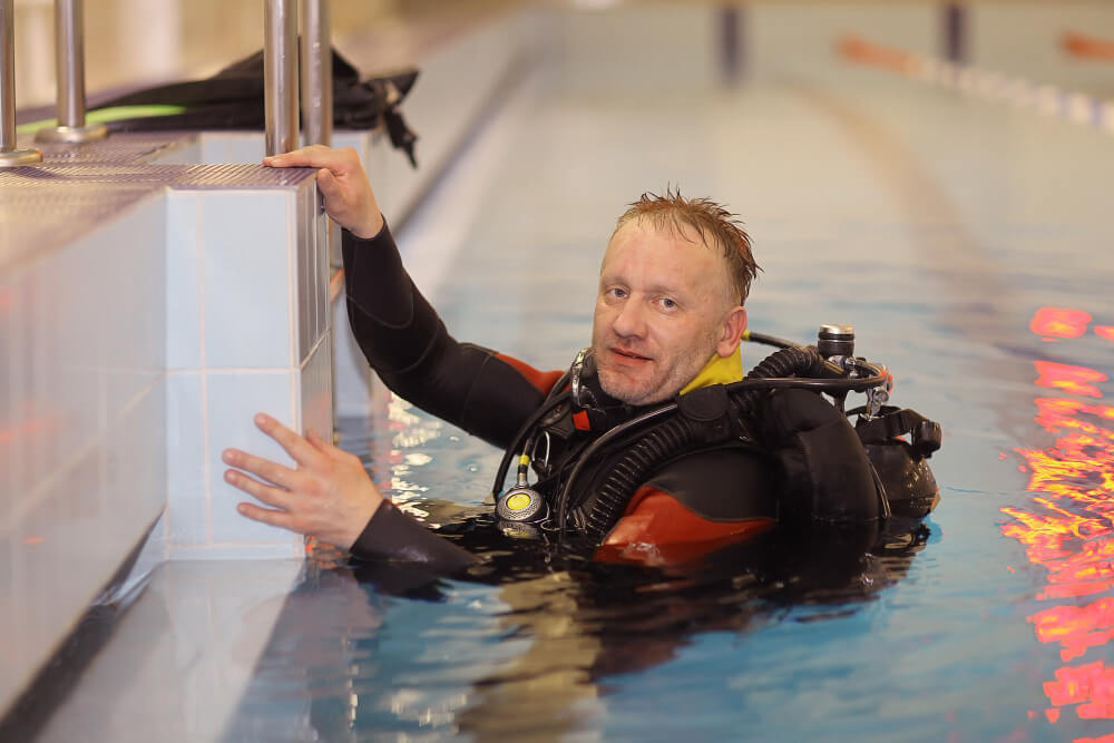 Taucher steigt aus Becken eines Indoor Tauchcenters