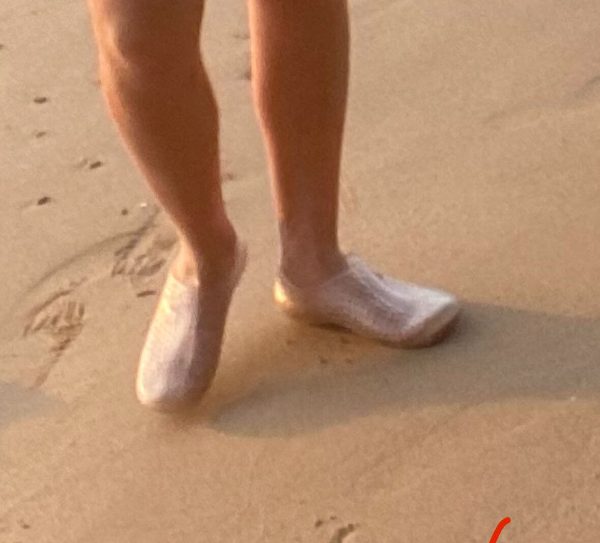 Schnorchler trägt durchsichtige Wasserschuhe am Sandstrand