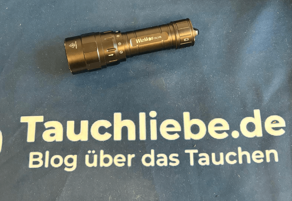Schwarze Wurkkos Tauchlampe liegt auf Tauchliebe.de Handtuch