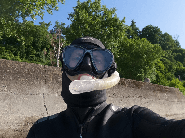 Schnorchler steht vor einer Steinkante an einem See