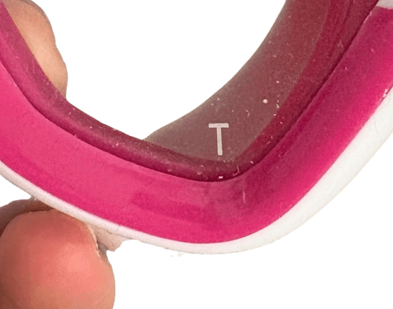 Glas einer pinken Tauchmaske mit Buchstabe T aufgedruckt