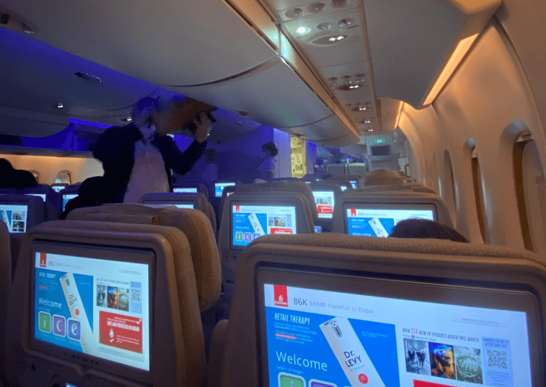 Mann räumt Handgepäckstasche im Flugzeug ein