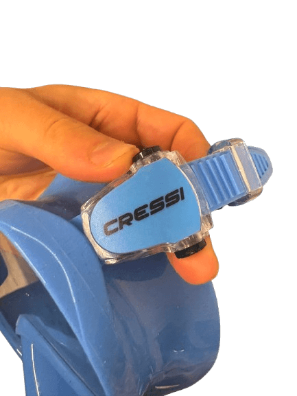 Zwei Finger drükcen schwarze Knöpfe um Kopfband an Tauchmaske zu verstellen