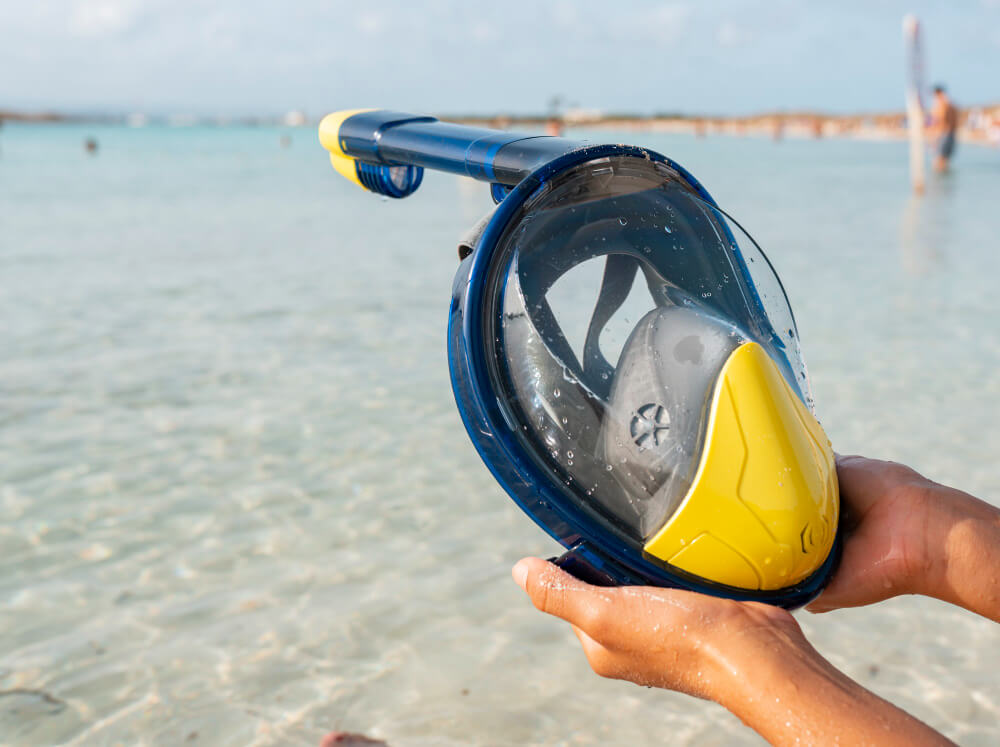 Billige Schnrochelmaske wird am Strand in der Hand gehalten