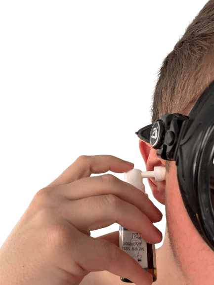 Taucher mit schwarzer Tauchmaske testet und sprüht das Dolphiner Ohrenspray in sein Ohr