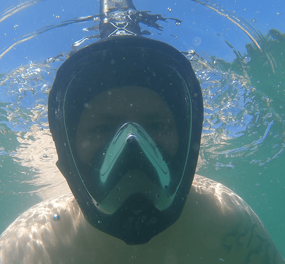 Schnorchler testet unterwasser ob Luftblasen aus seiner Vollgesichtsmaske austreten