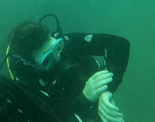 Taucher testet einen schwarzen Tauchcomputer unterwasser 