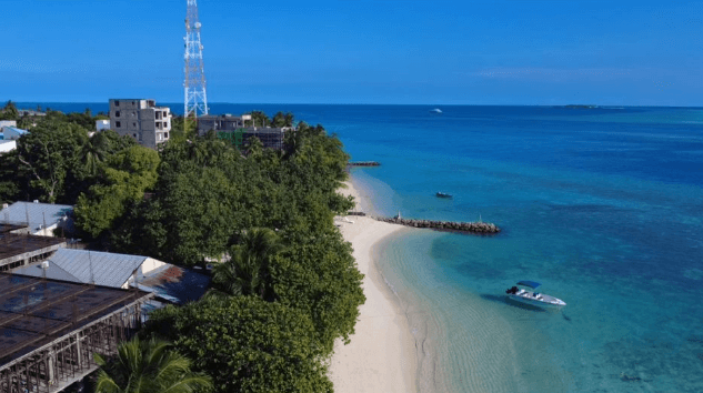 Drohnenaufnahme Strand und Bucht sowie Gebäude mit Bäumen und Funkmast in Rasdhoo