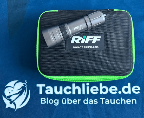 Riff Tauchlampe liegt auf schwarzem Softcase auf Tauchliebe Handtuch