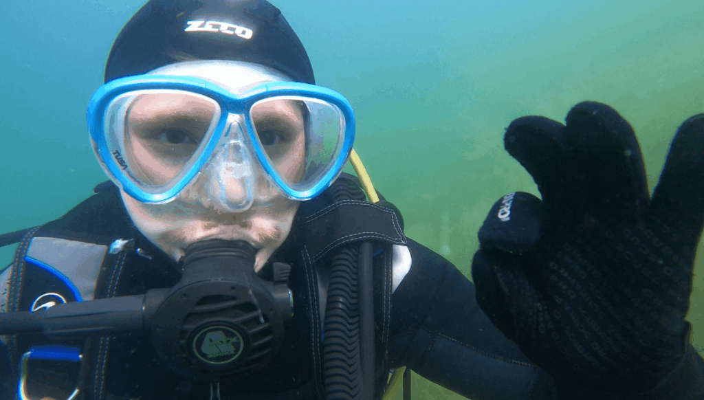 Taucher mit Oberlippenbart im grünen Seewasser abgetaucht