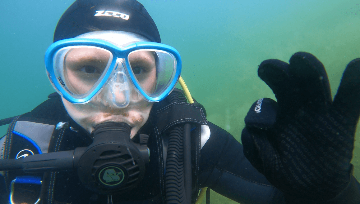 Taucher mit Bart trägt eine hellblaue Tauchmaske unterwasser