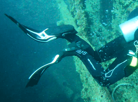 Taucher trägt Neopren Füßlinge und gut sitzende weiße Flossen unterwasser