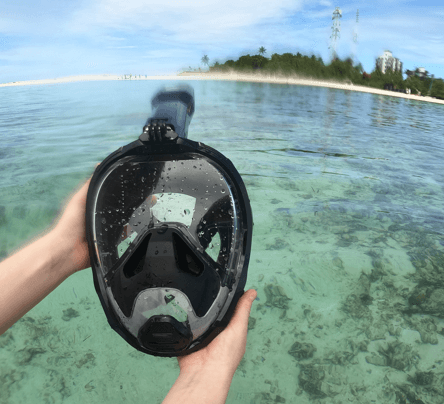 schwarze Khroom Seaview Pro Plus Schnorchelmaske wird im Meer in der Hand gehalten