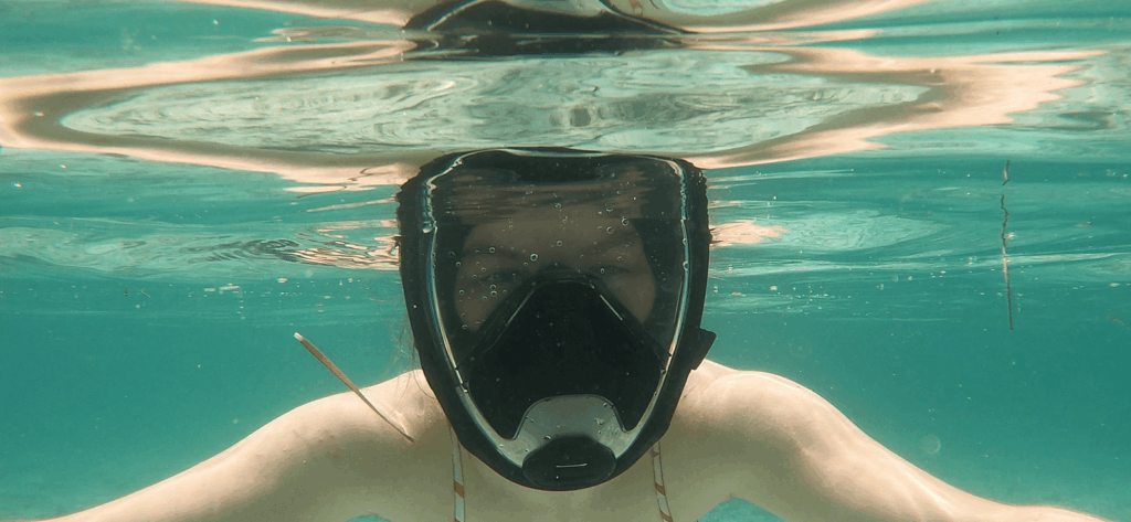 Schnorchlerin trägt schwarze Schnorchelmaske unterwasser