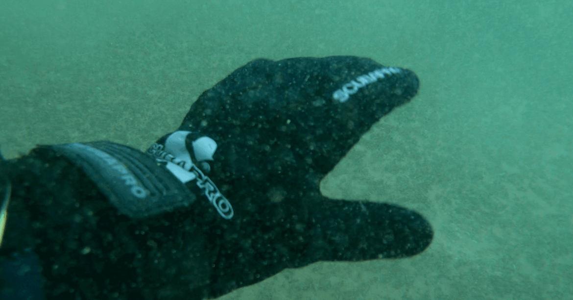 Taucher testet schwarzen Neoprenhandschuh unterwasser im See