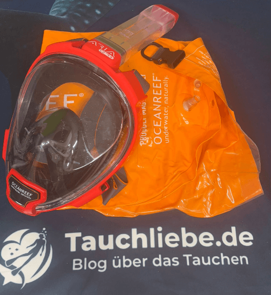 Rote Oceanreef Aria QR+ Schnorchelmaske liegt auf orangener Drybag