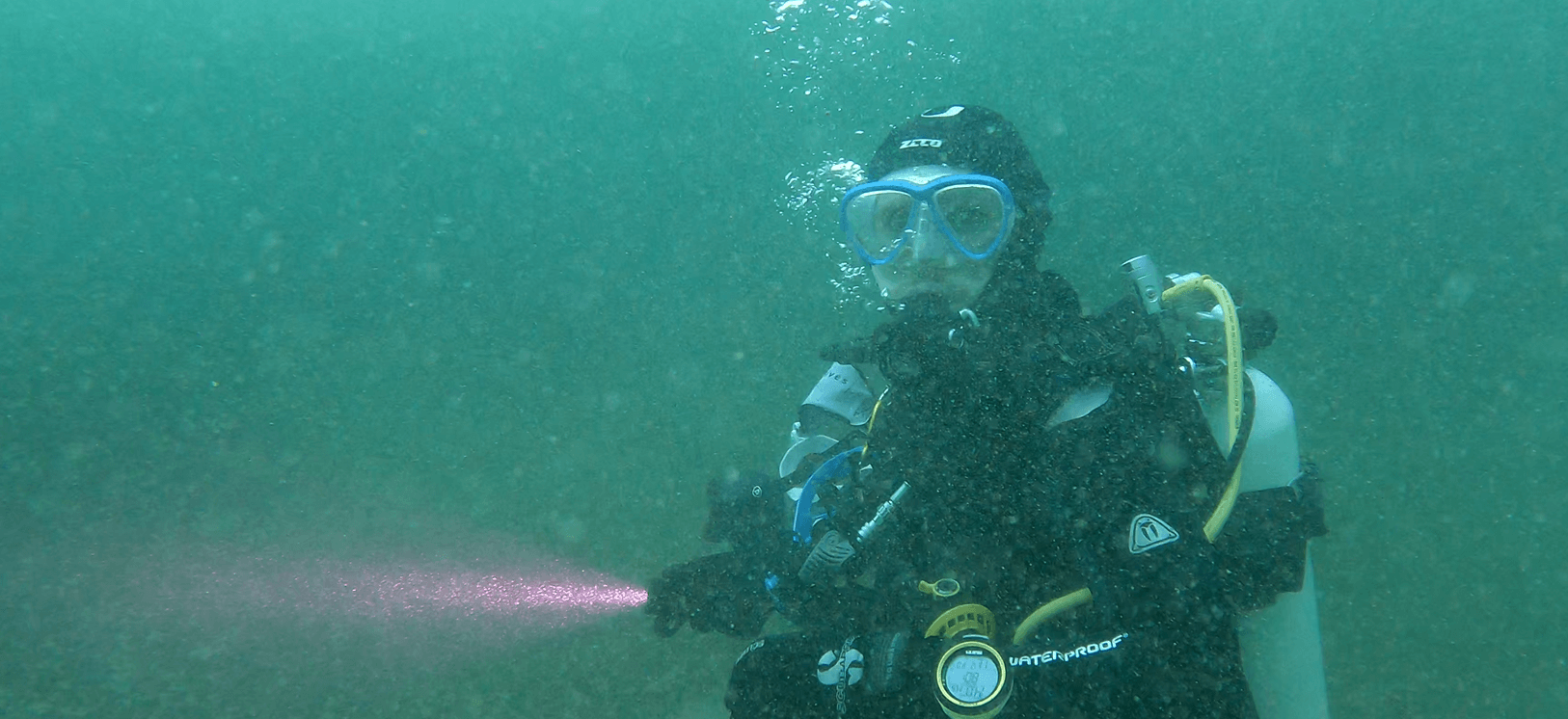 Taucher unter Wasser mit Tauchlampe in der Hand während eines Tauchgangs