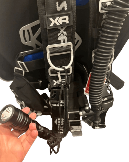 Tauchlampe mit Handschlaufe und Karabiner am D-Ring des Jackets befestigt