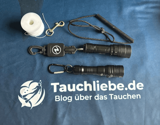 Tauchlampen mit verschiedenen Befestigungsarten wie Boltsnap, Karabiner, Retractor und Leine im Vergleich