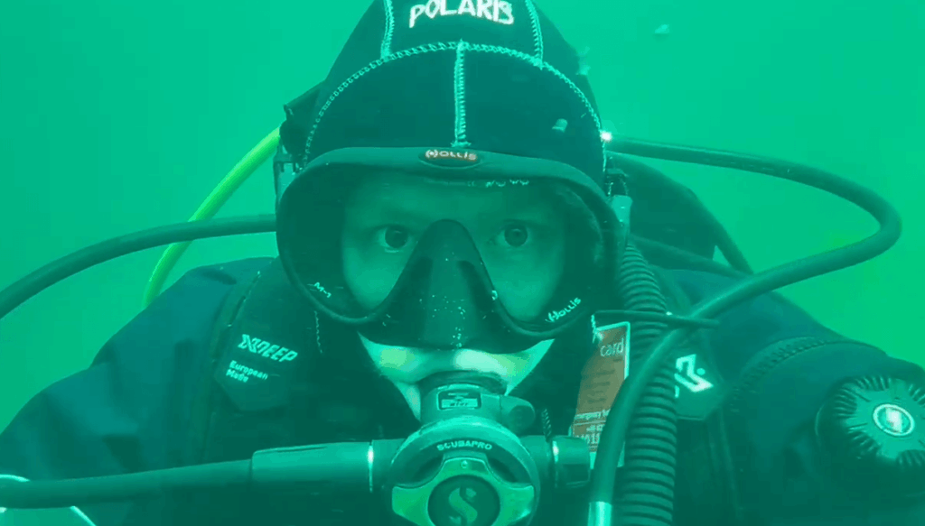 Taucher testet Hollis M1 Tauchmaske unterwasser und schaut frontal in Kamera