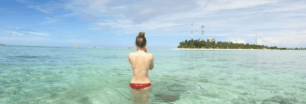 schnorchlerin testet ihre schnorchelausrüstung vor einer Insel auf den Malediven