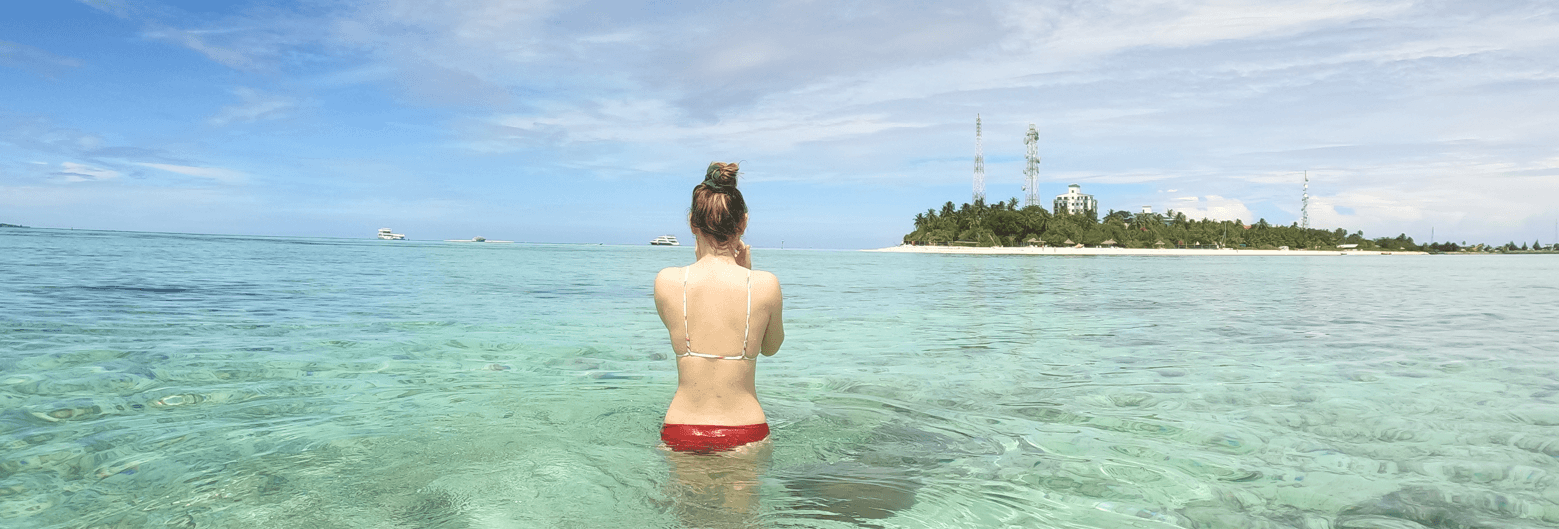 schnorchlerin testet ihre schnorchelausrüstung vor einer Insel auf den Malediven