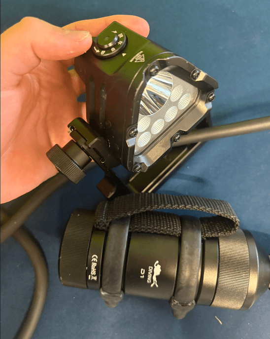 Schwarze Wurkkos D1 Tauchlampe neben Akkubehälter